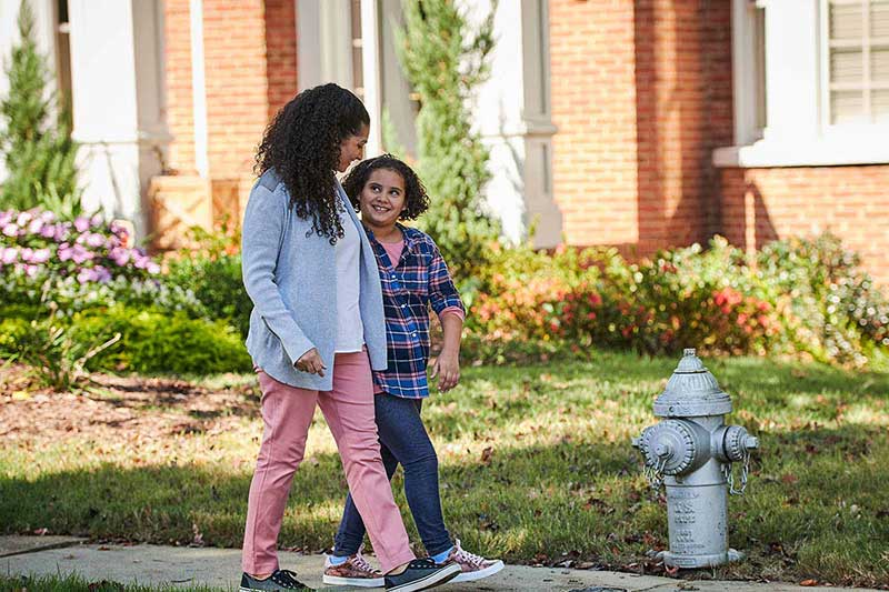 mom and daughter taking a walk on sidewalk